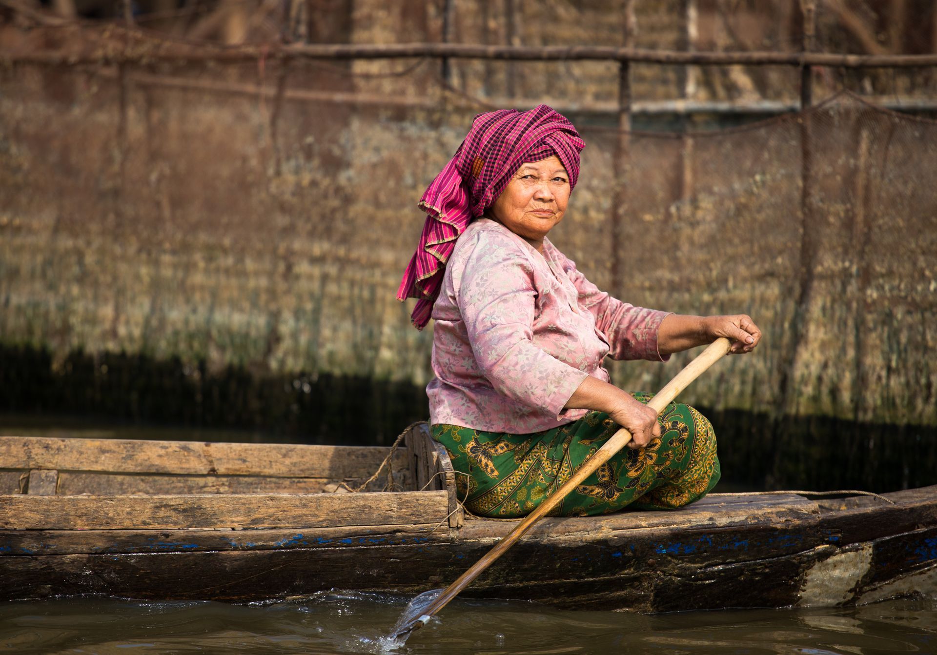 A woman is rowing a boat in the water.