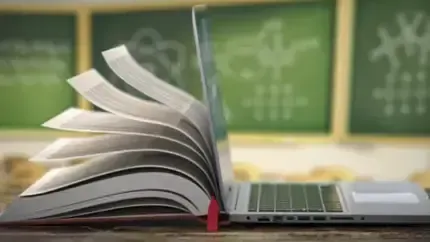 An open book is sitting next to a laptop computer on a table.