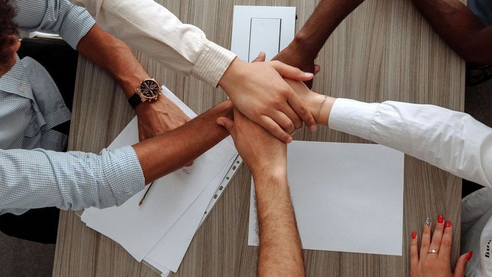 A group of people are putting their hands together in a circle.