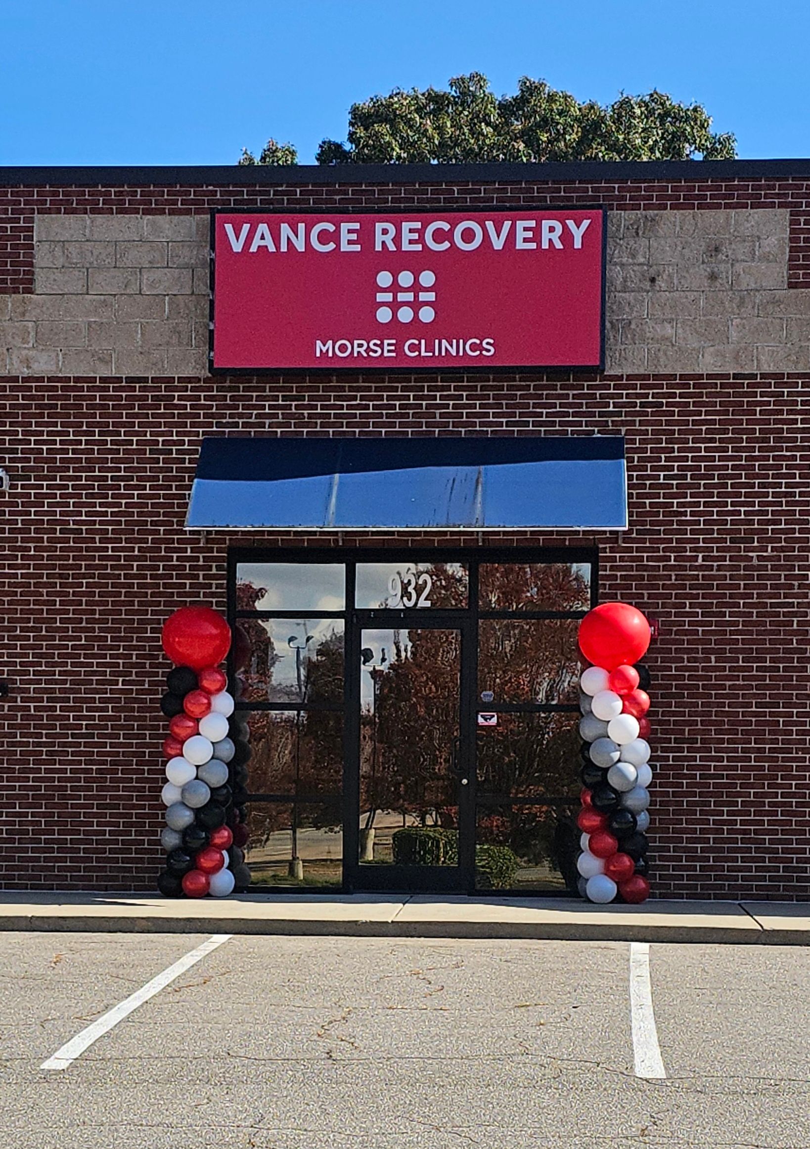 The storefront for Vance Recovery, a clinic with a red sign, black awning, and balloon pillars at the entrance.
