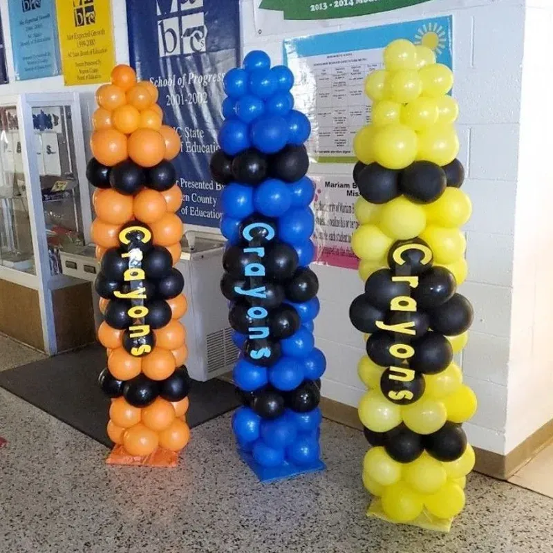 Three balloon crayon decorations in orange, blue, and yellow with black accents and