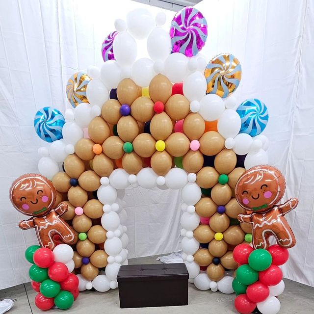 Gingerbread house arch made of balloons, with gingerbread man balloons on either side.
