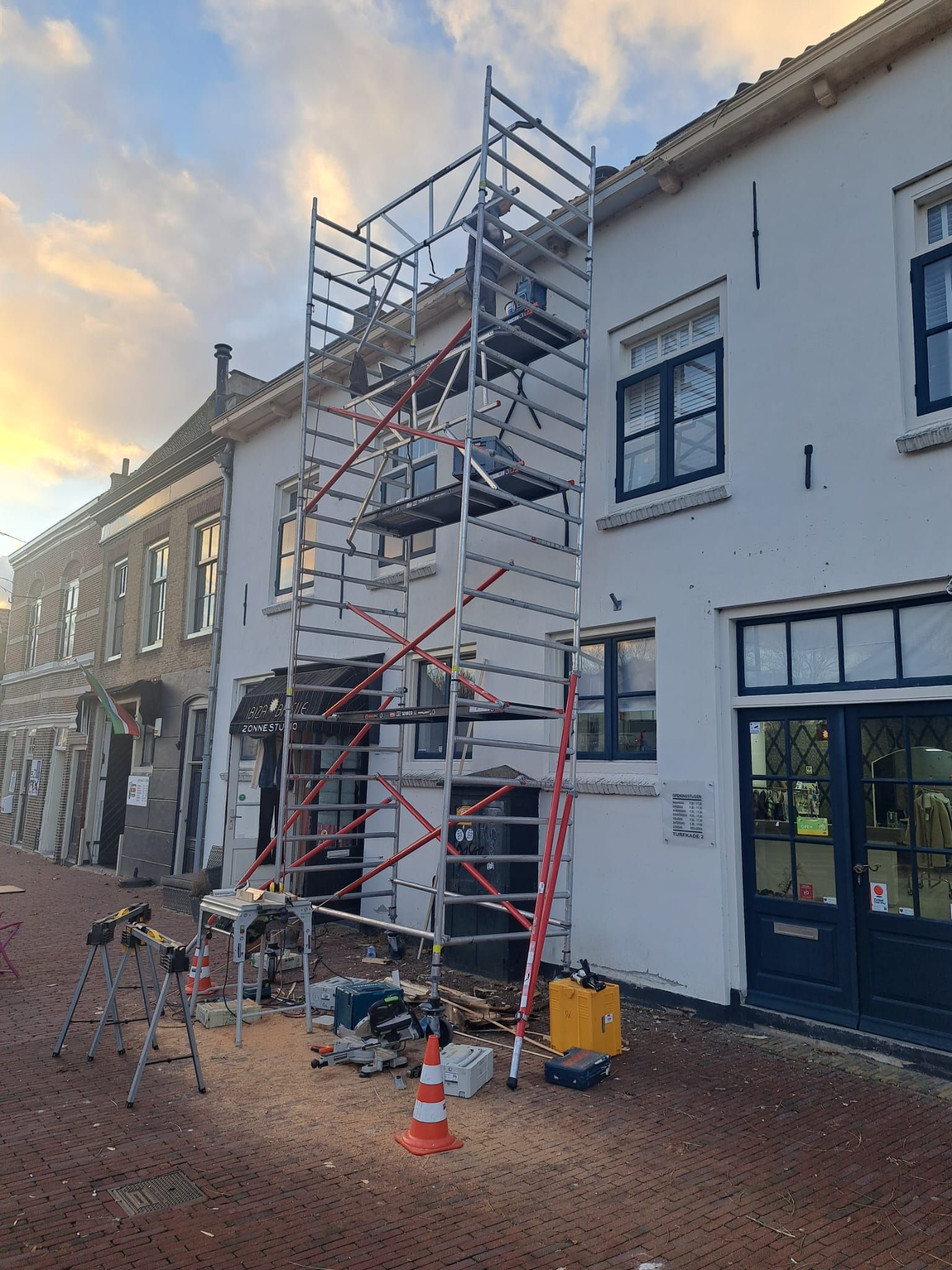 Voor een wit gebouw staat een steiger.