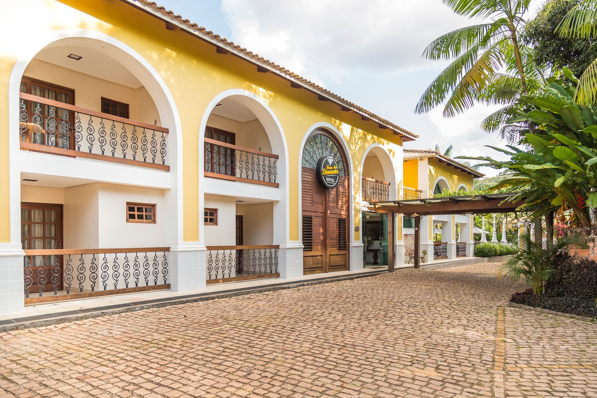Um grande edifício amarelo e branco com uma entrada de tijolos na frente