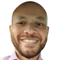 A bald man with a beard is smiling and wearing a pink shirt.