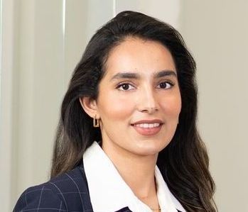 A woman in a suit and white shirt is smiling for the camera.