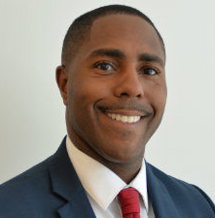A man in a suit and tie is smiling for the camera.