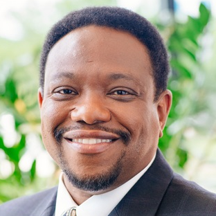 A man in a suit and tie is smiling for the camera.
