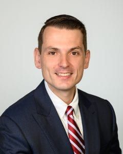 A man in a suit and tie is smiling for the camera.