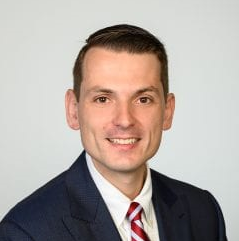 A man in a suit and tie is smiling for the camera.