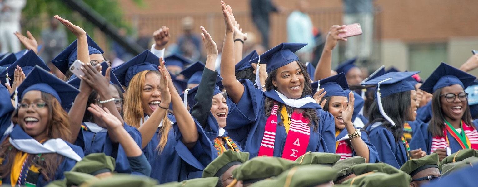 A group of graduates are standing in a line with their arms in the air.