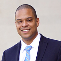A man in a suit and tie is smiling for the camera