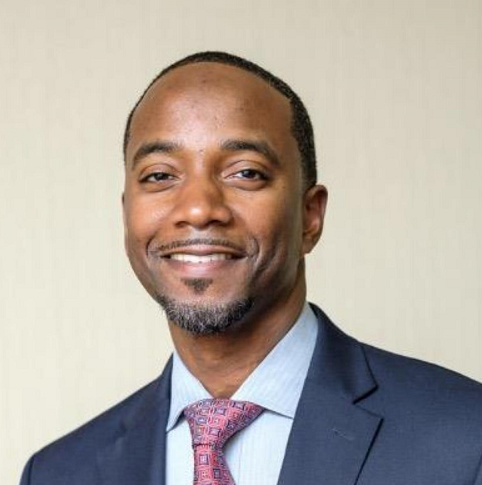 A man in a suit and tie is smiling for the camera.