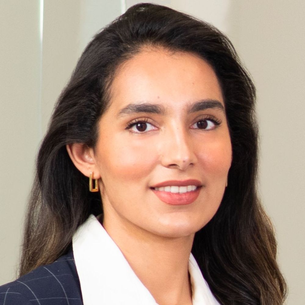 A woman wearing a suit and earrings is smiling for the camera.