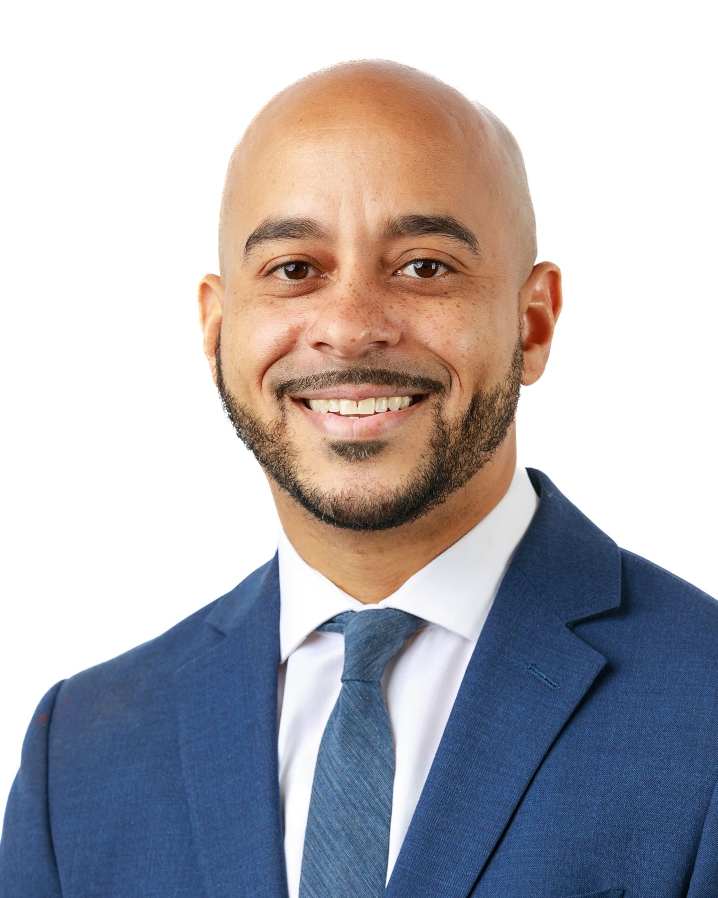 A bald man with a beard is wearing a blue suit and tie.