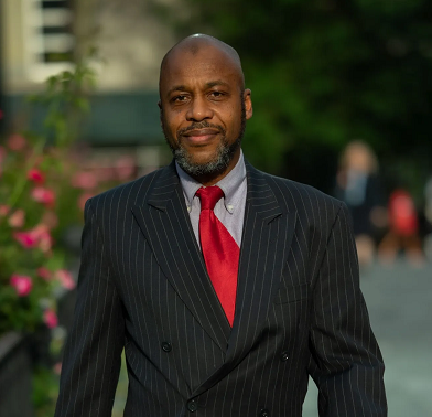 A man in a suit and red tie is smiling for the camera