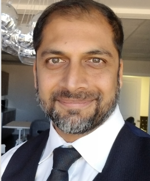A man with a beard and tie is smiling for the camera