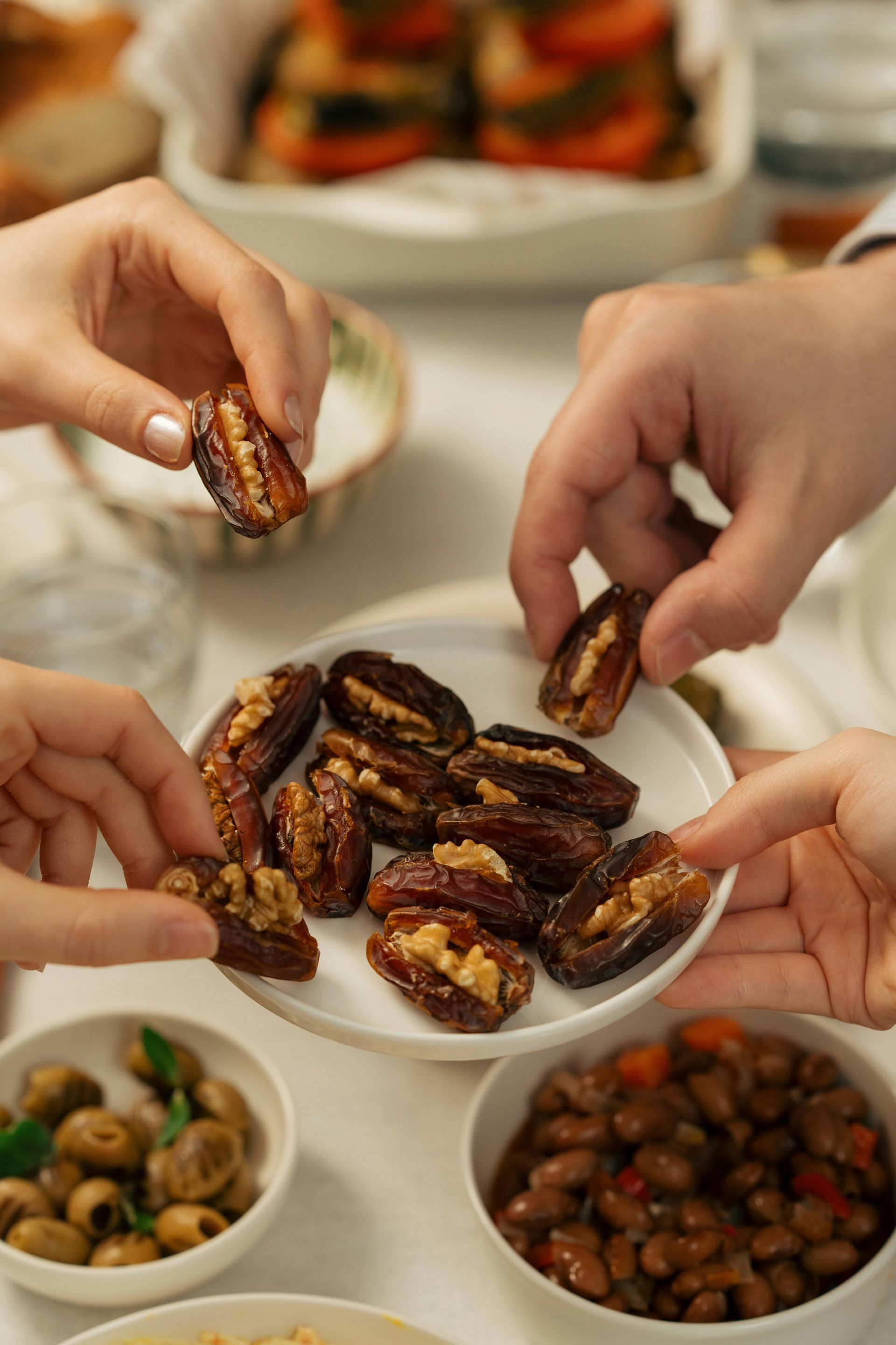 A group of people are eating dates with walnuts on a plate.