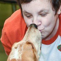A woman is kissing a dog on the nose.