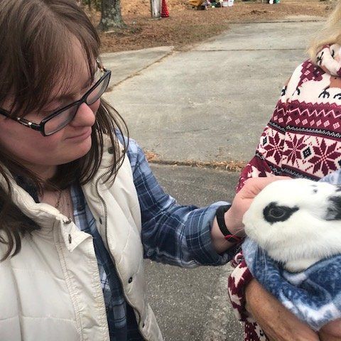 A woman is holding a black and white rabbit in her arms.