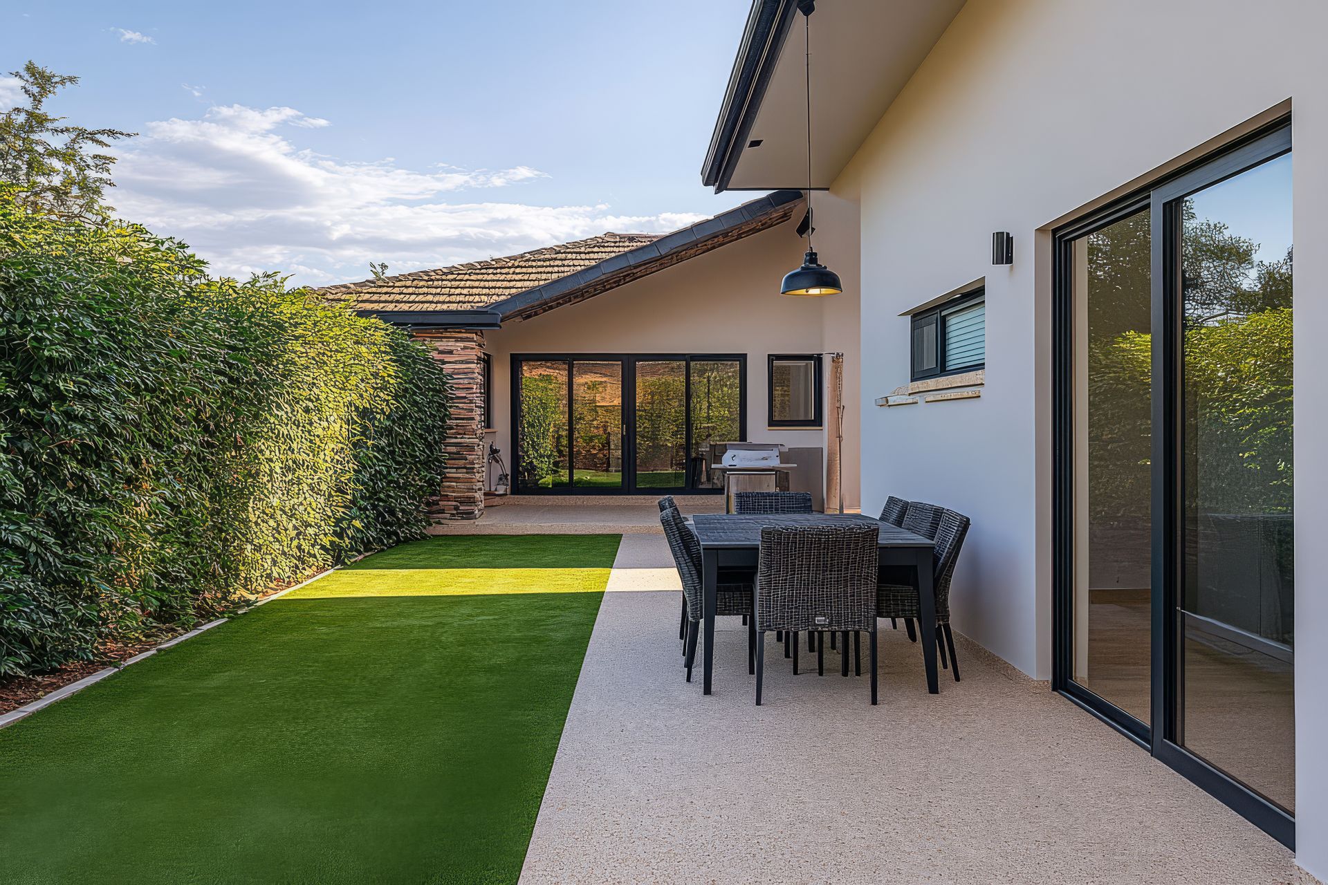 A patio with a table and chairs in the backyard of a house.
