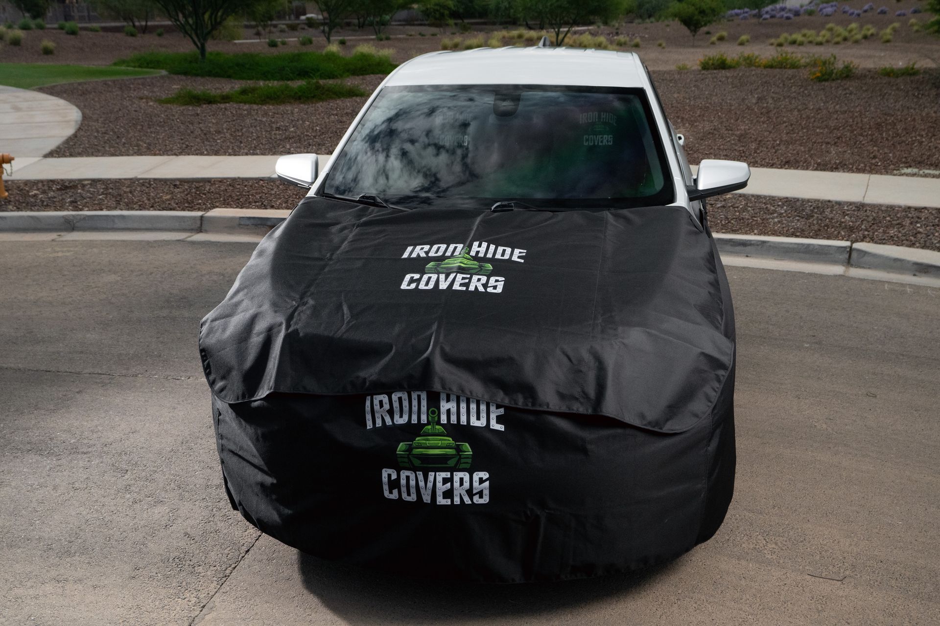 Black covered vehicle with Iron Hide Covers text parked on a street.