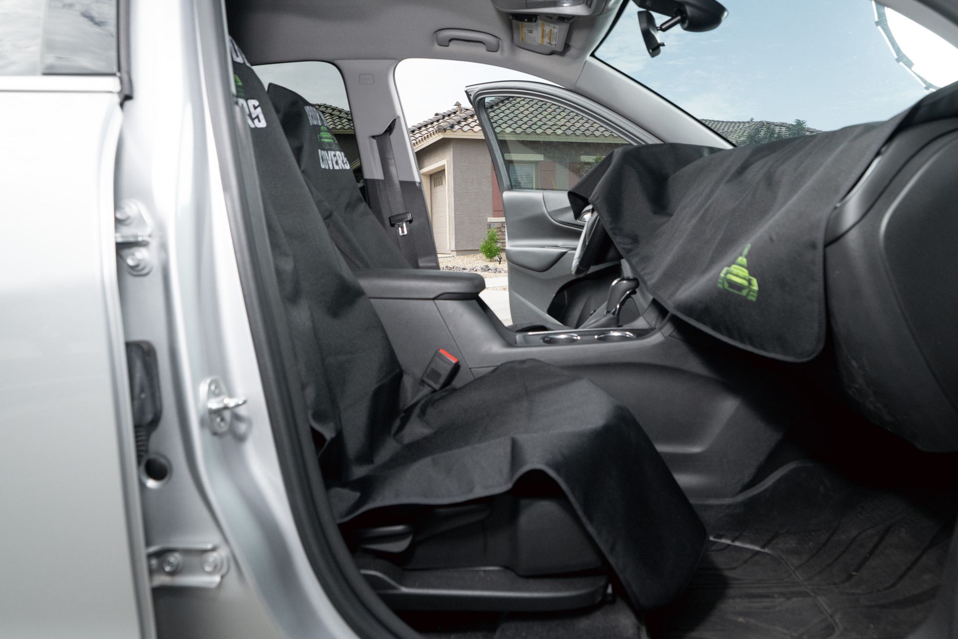 Car interior with the passenger seat removed or folded, showing black seat covers and open door.