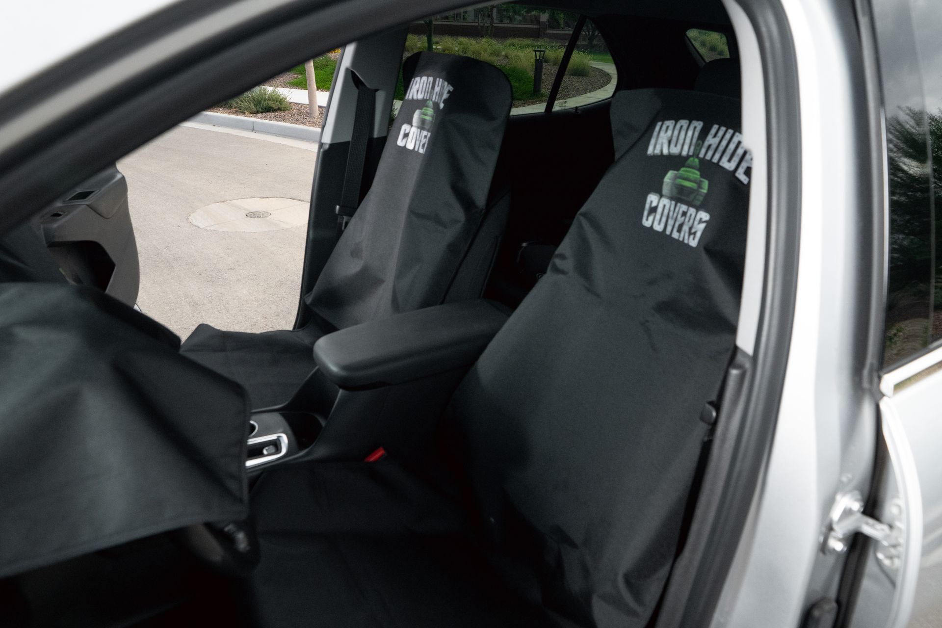 Car interior with black racing seats and seat covers, viewed through the open driver’s door.