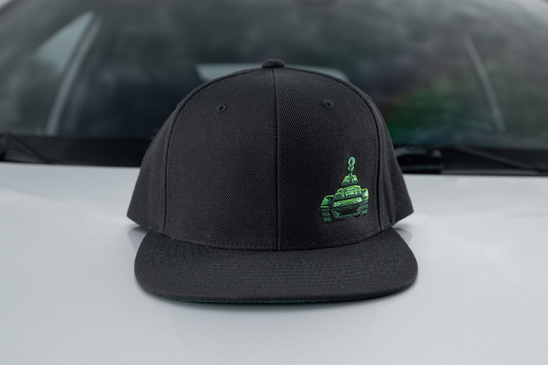 Black baseball cap with a green embroidered logo on the front.