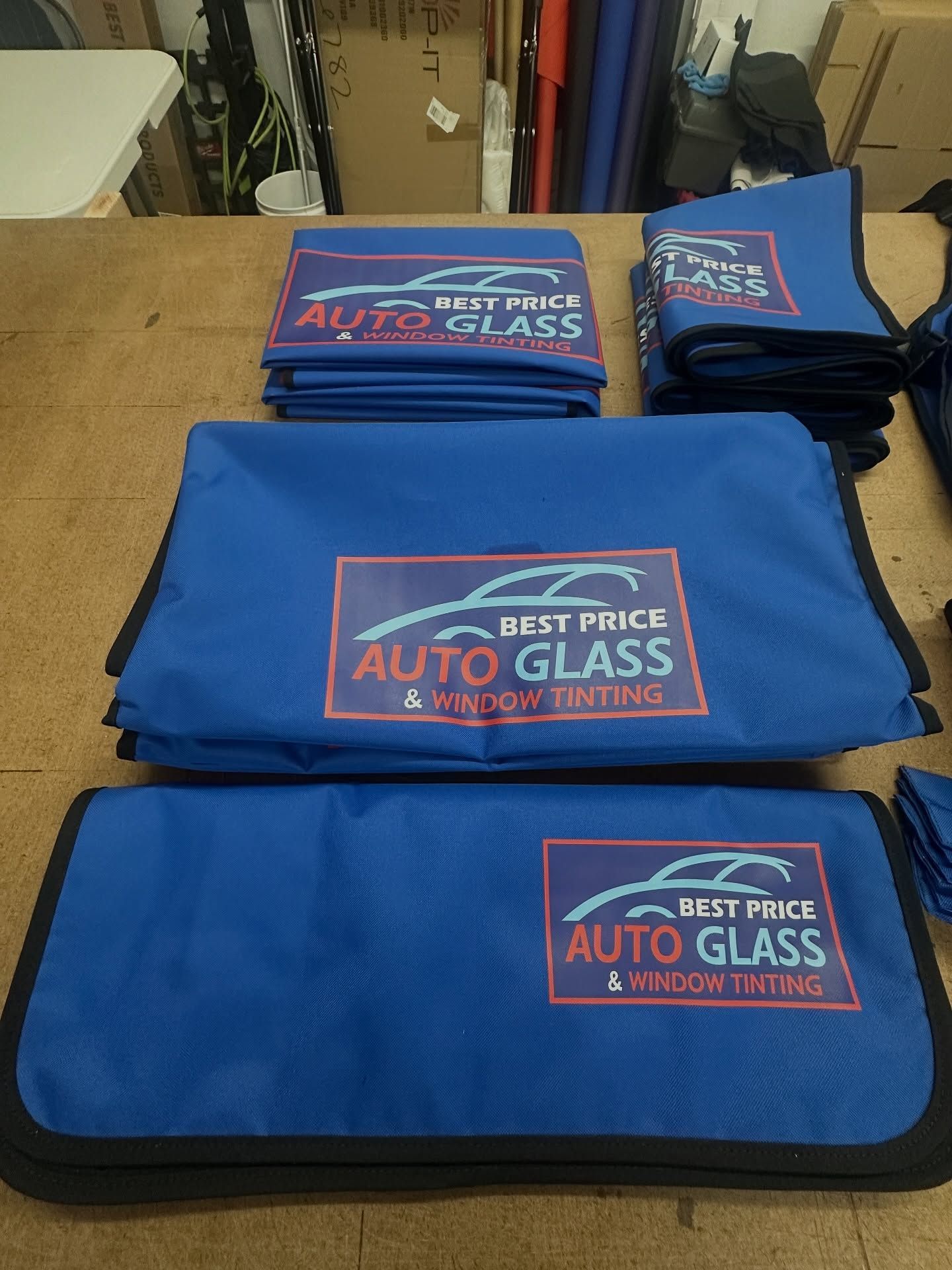 Stacked blue Best Price Auto Glass covers on a table
