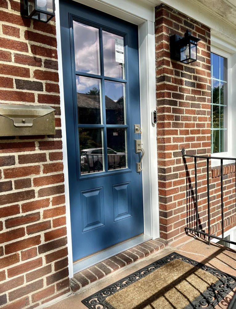 Blue front door with glass panes, brick exterior, and brass mailbox.