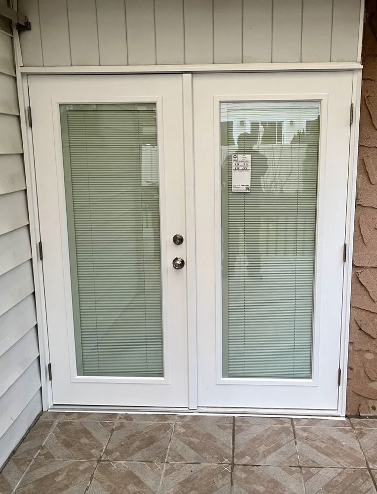 White double doors with glass panels and blinds; on a tiled patio.
