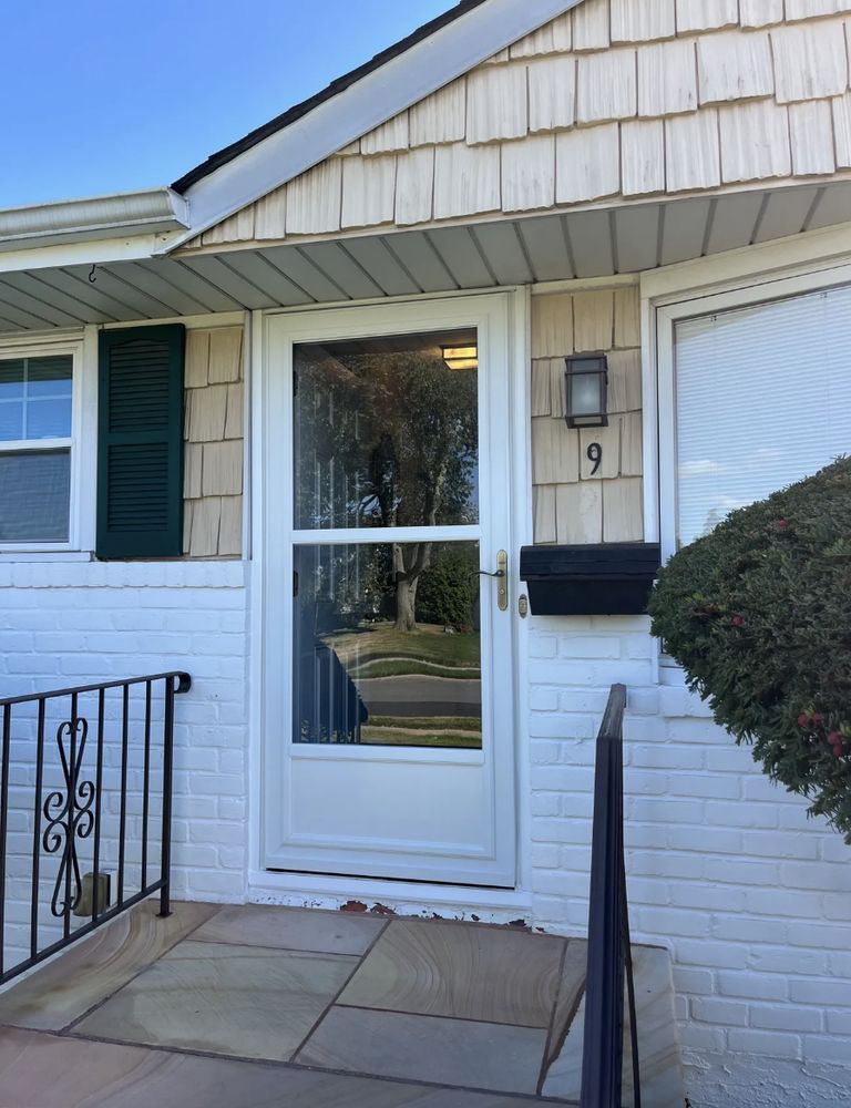 White front door of house number 9, with storm door, mailbox, and brick exterior.