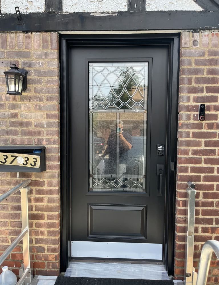 Black front door with glass panel, brick house exterior, mailbox, sconce, address 37-33.