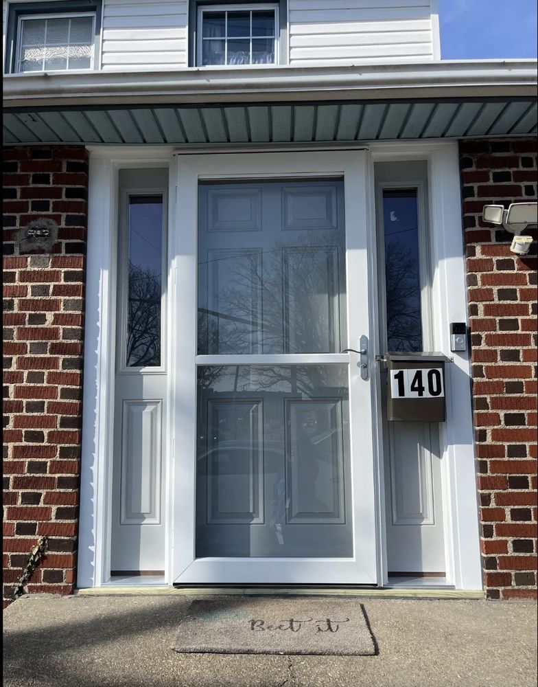 Front door of a brick house with a white storm door and mailbox. Address number 140.
