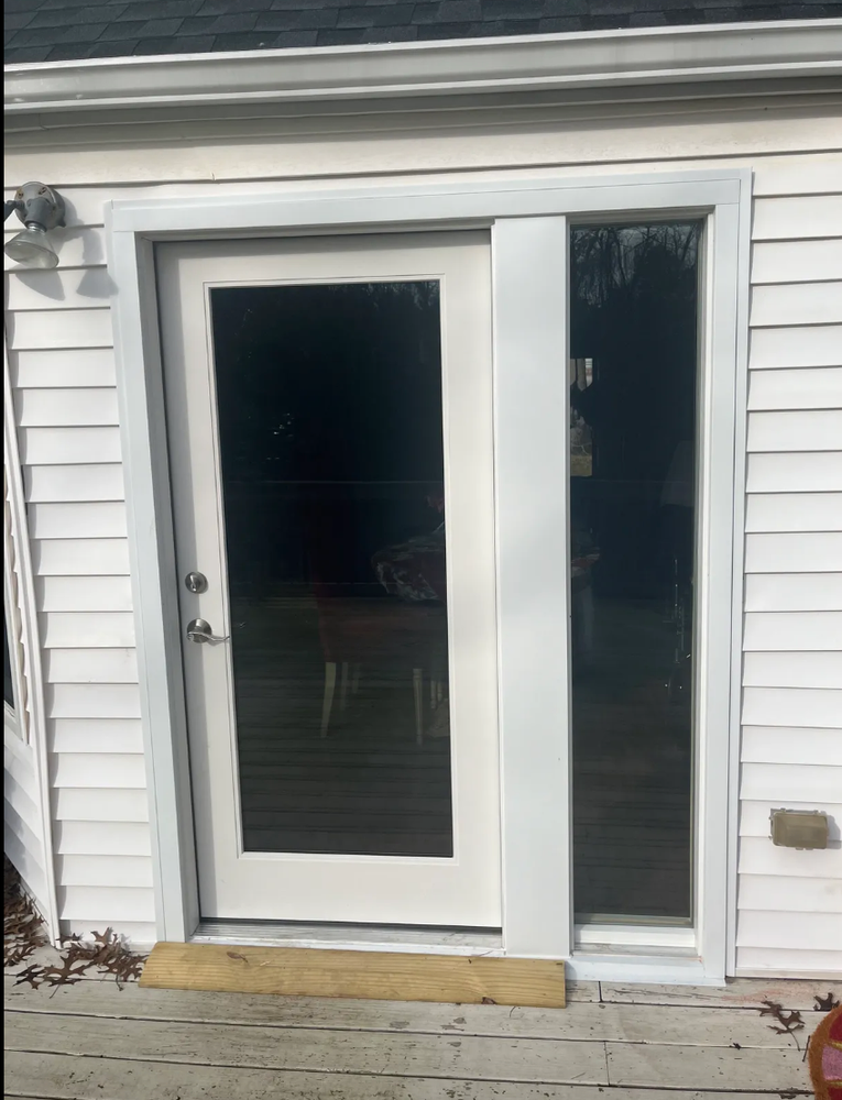White door with glass panel and side window on a white house, surrounded by white trim.