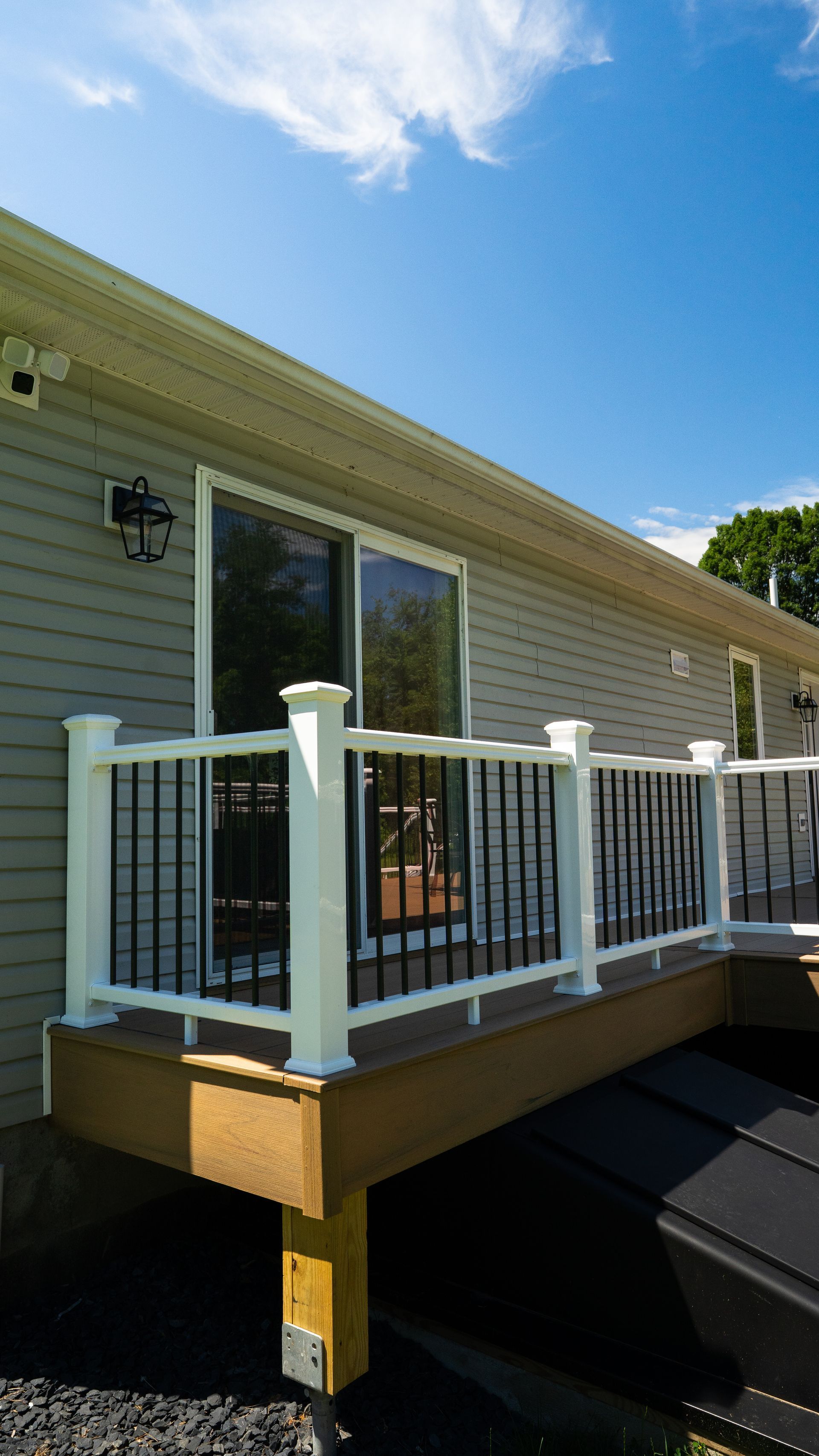 White-railed deck attached to a beige house under a blue sky.