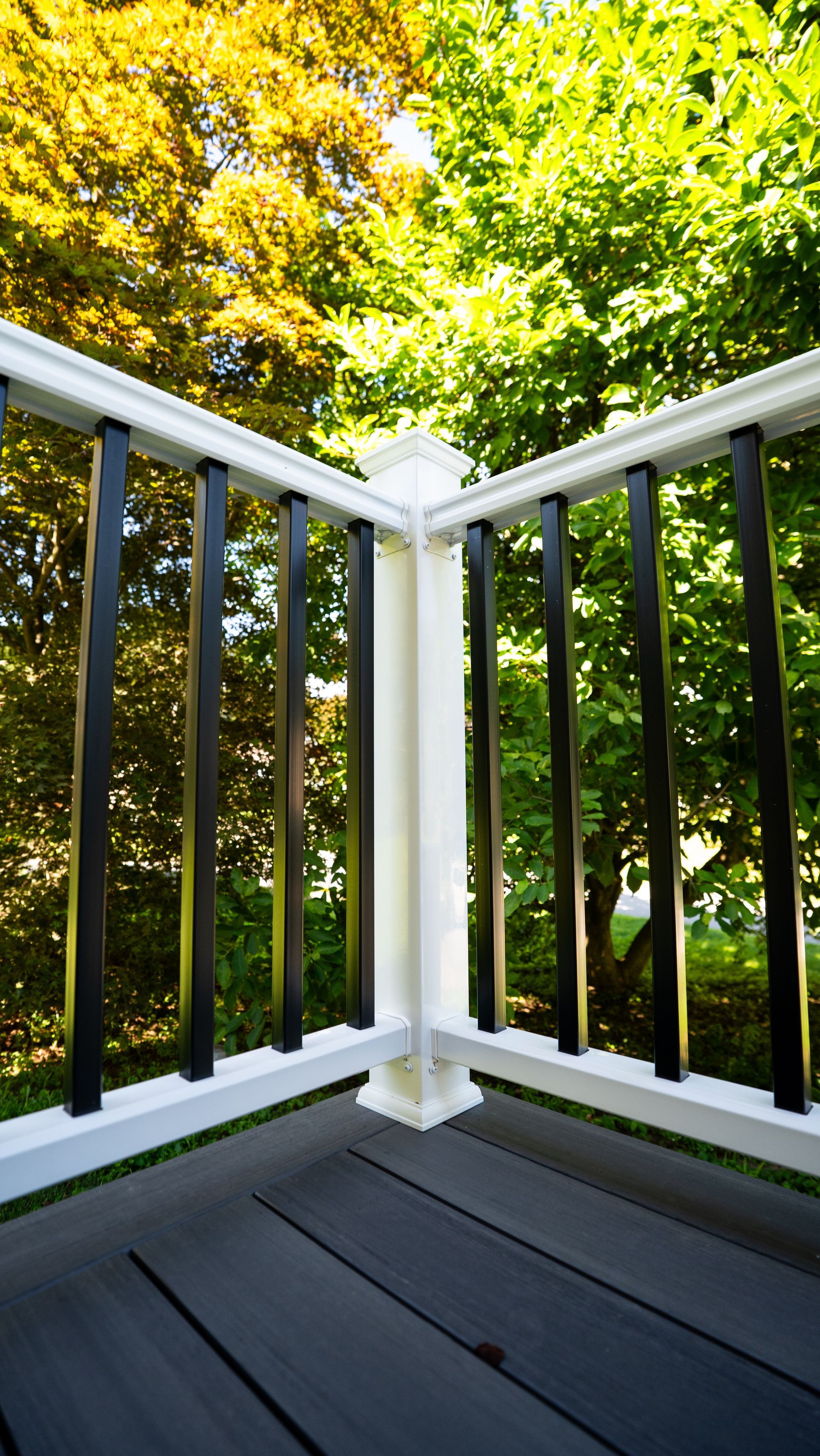 White porch railing corner overlooking green trees and yellow autumn foliage