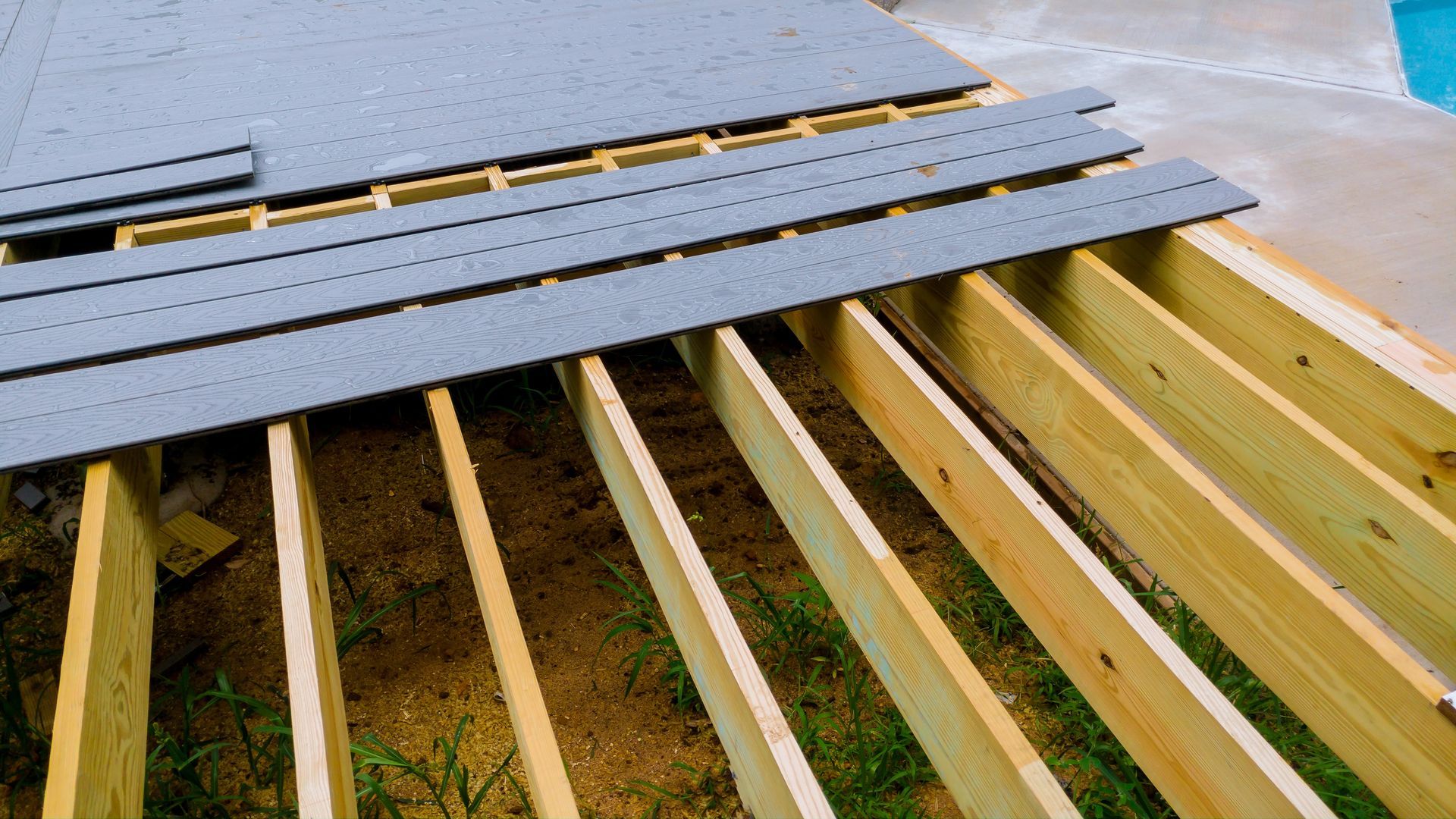 Workers installing dark roof panels on a wooden roof frame under construction