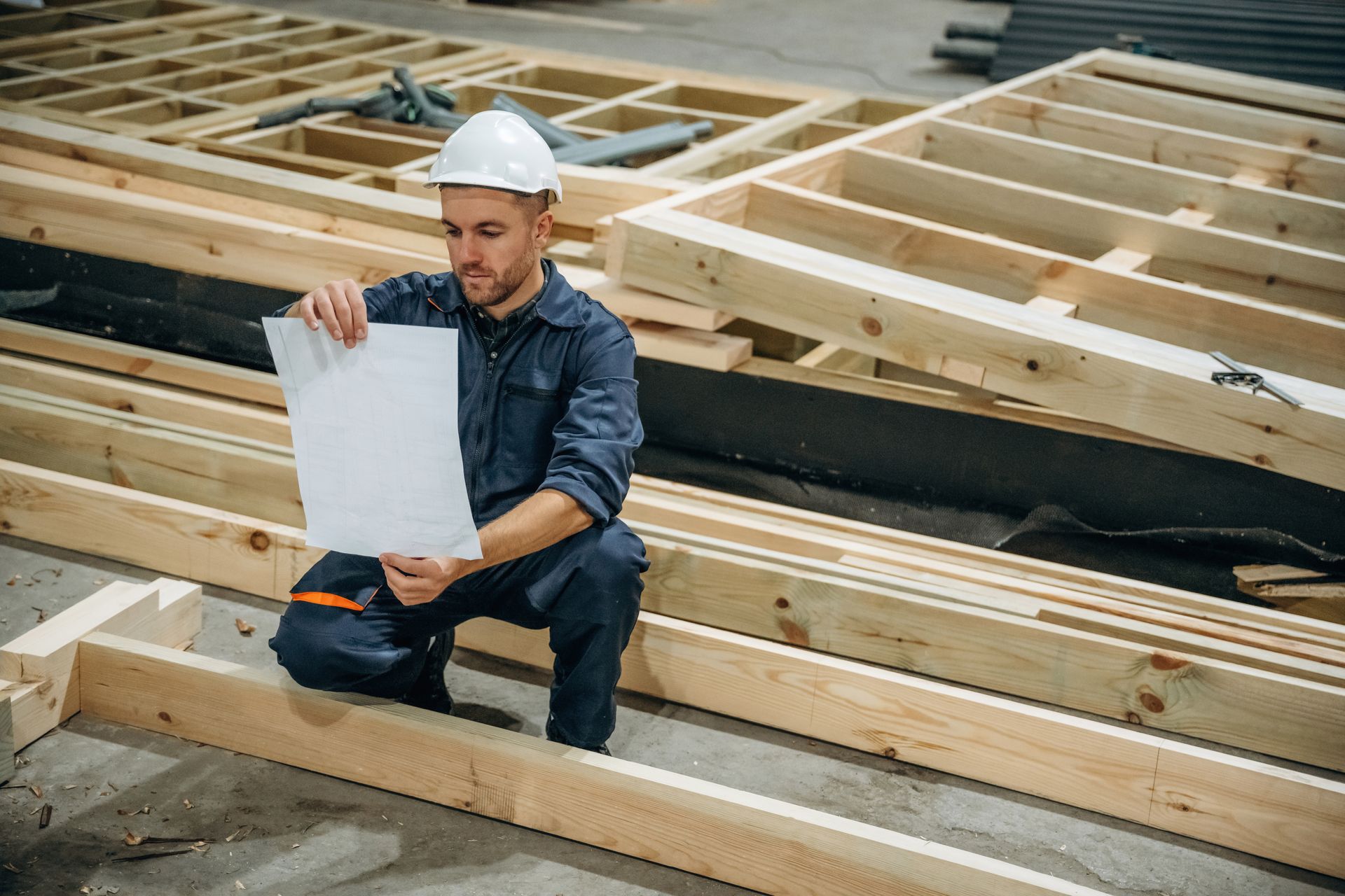 Construction worker reviewing plans at a wooden building frame site