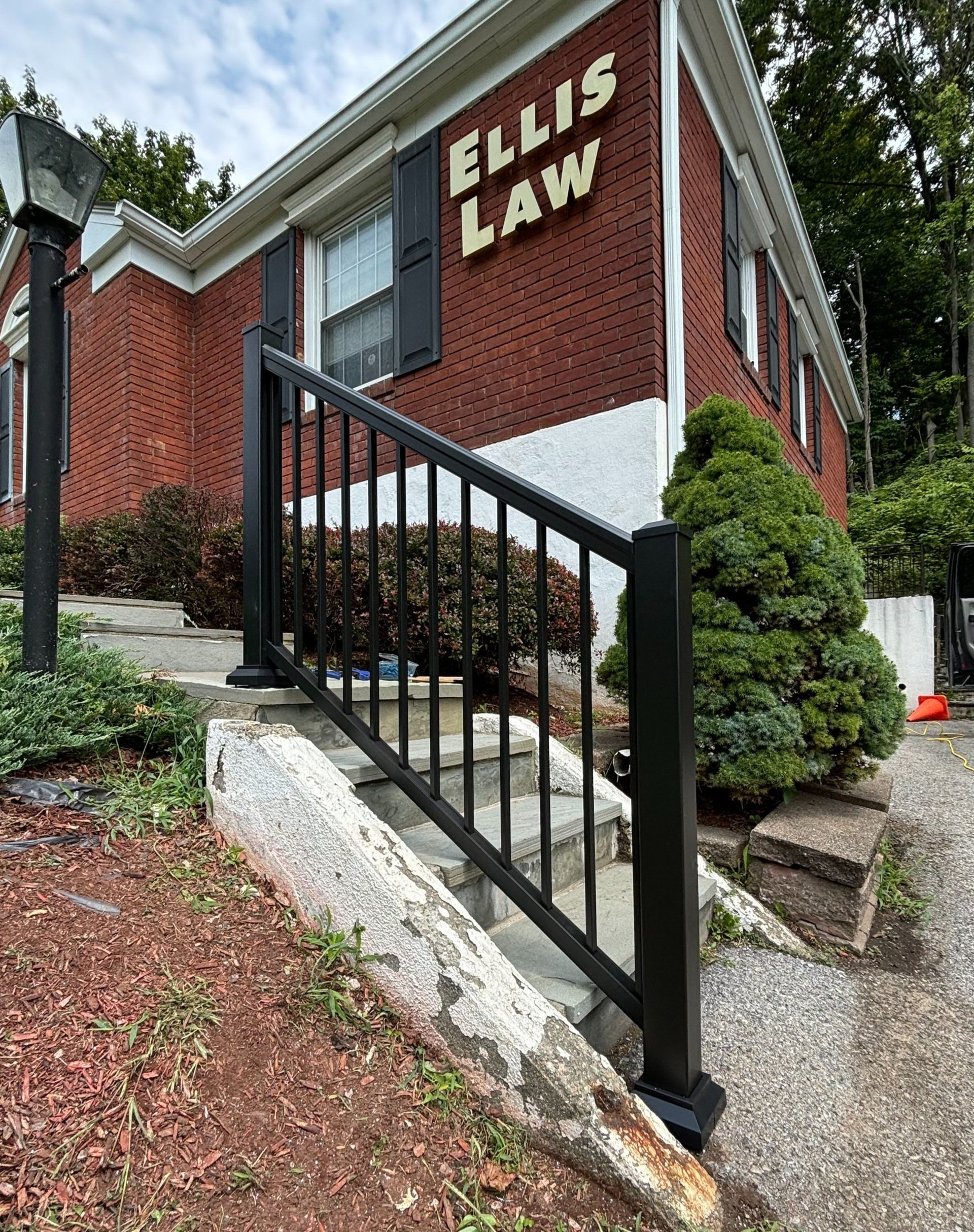 A brick building with stairs leading up to it and a black railing.