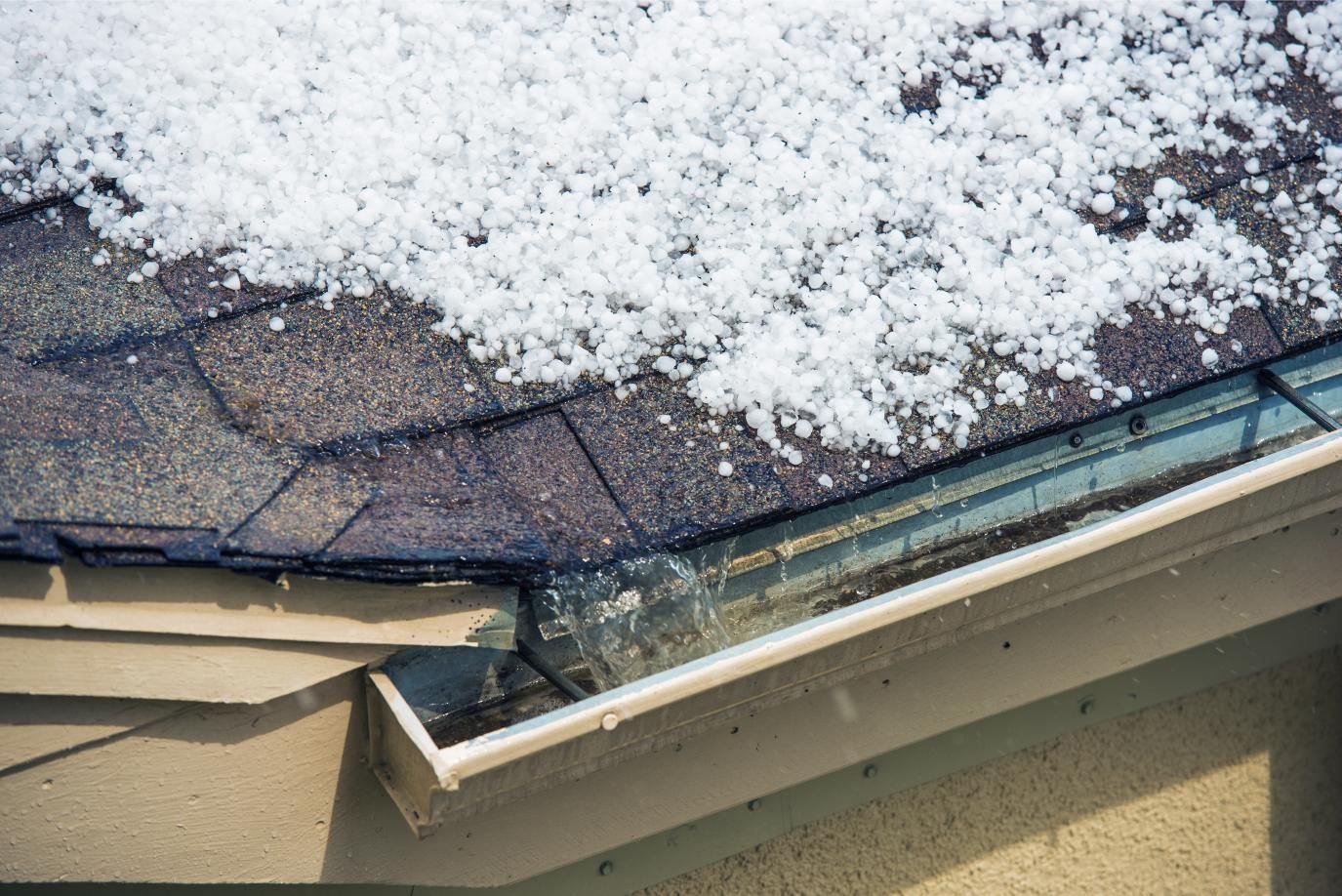 Snow-covered roof with damaged gutter and eaves in the corner of a house