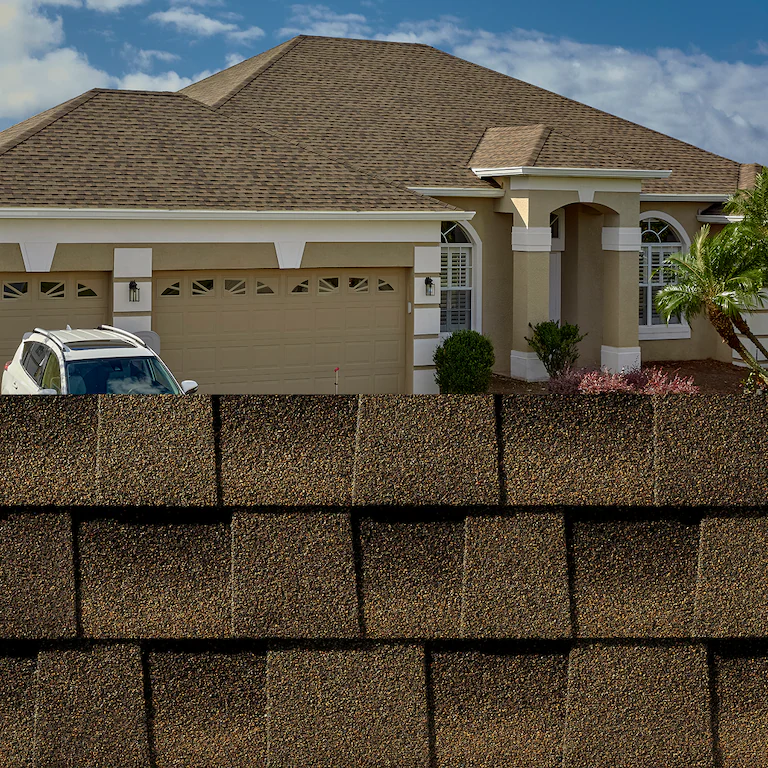 House behind a tall brick wall, with a tan roof and a parked white car on the left