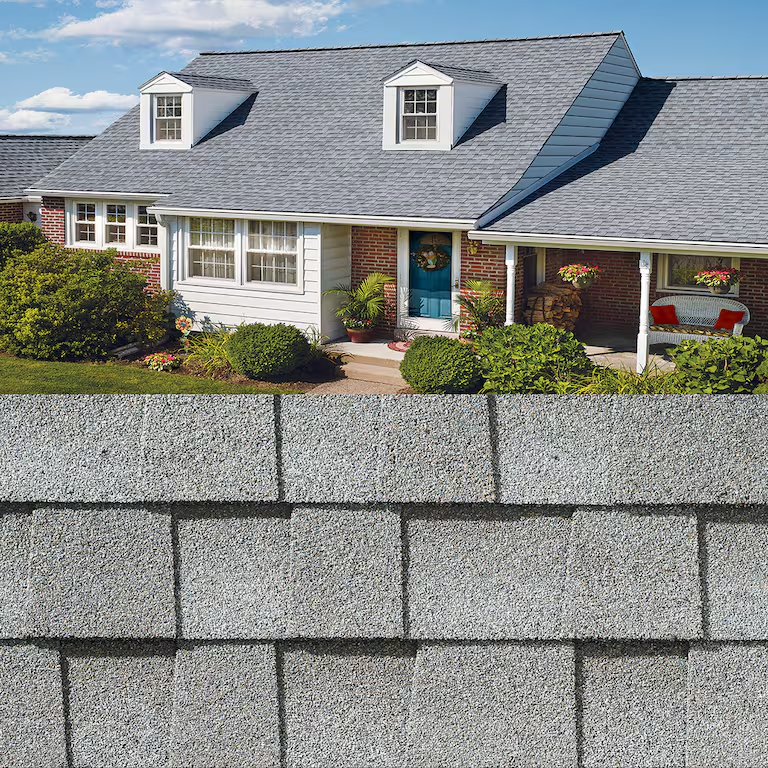 Suburban house with blue-gray roof above a close-up of gray asphalt roof shingles