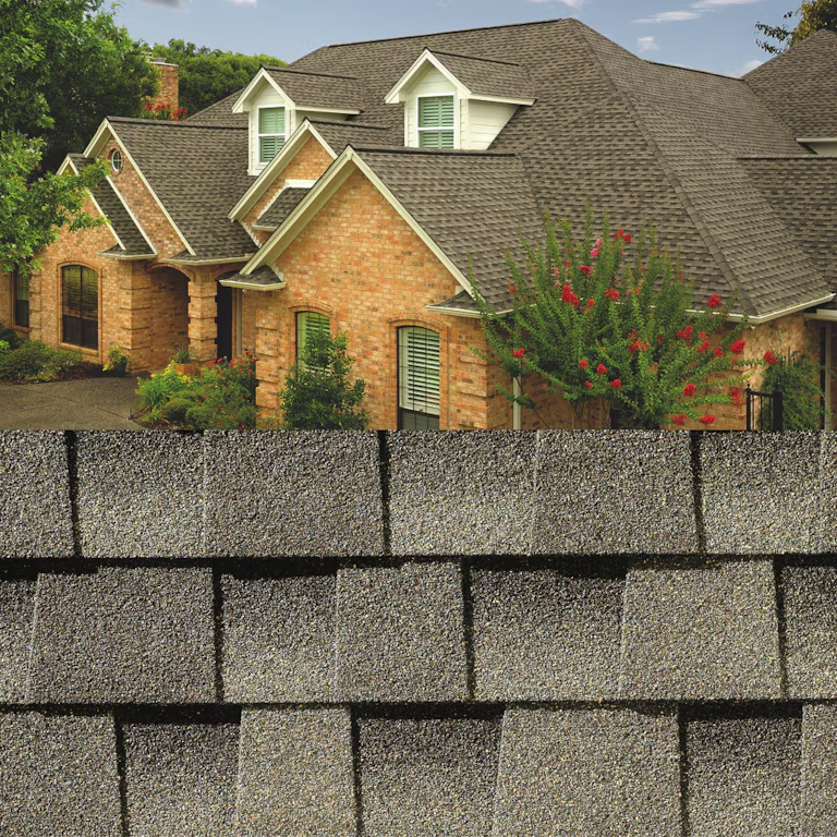 Suburban brick house behind a gray shingle roof in the foreground