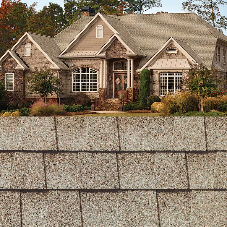 Large beige suburban house behind a stone wall, with landscaped yard and dormer windows.