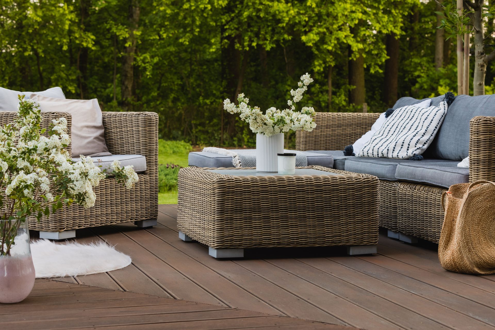 Outdoor patio seating with patterned wicker sofas, matching ottoman, and cushions on a wooden deck