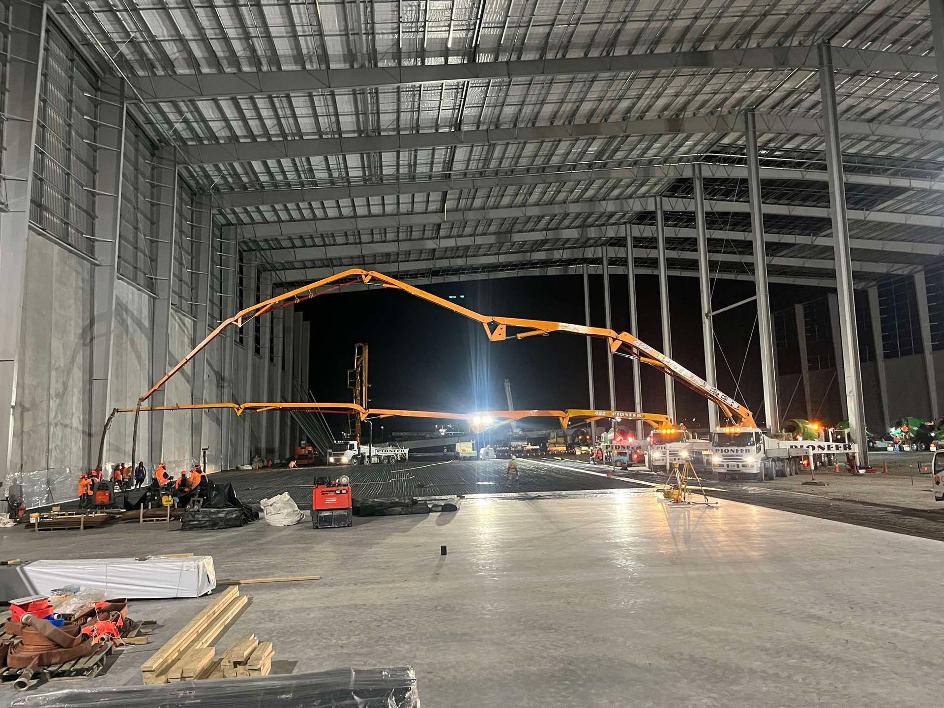 A concrete pump is being used to pour concrete into a large warehouse.