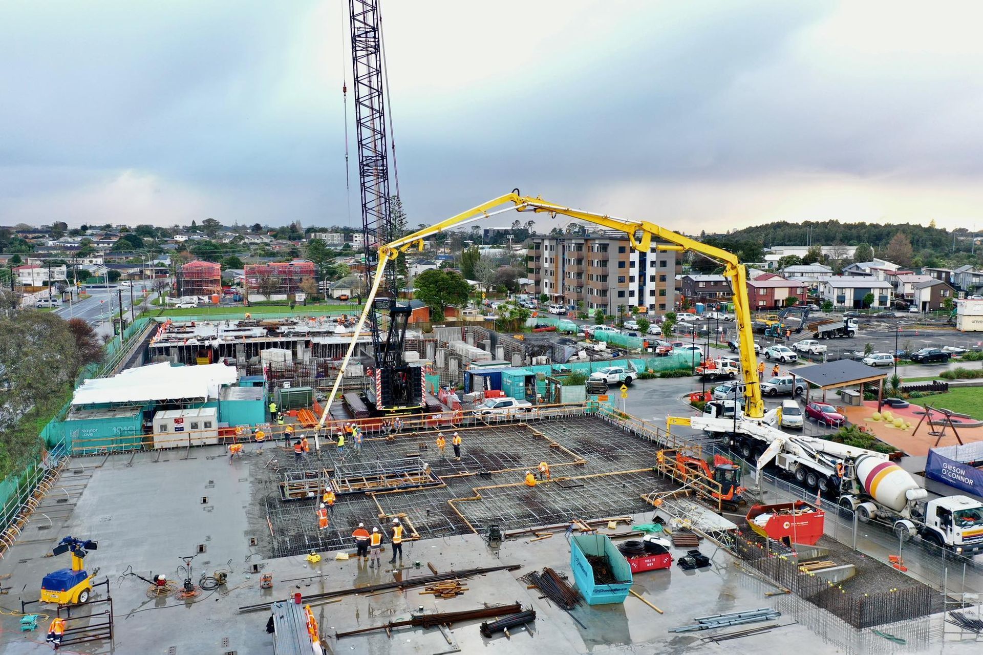 An aerial view of a construction site with a crane and a concrete pump.