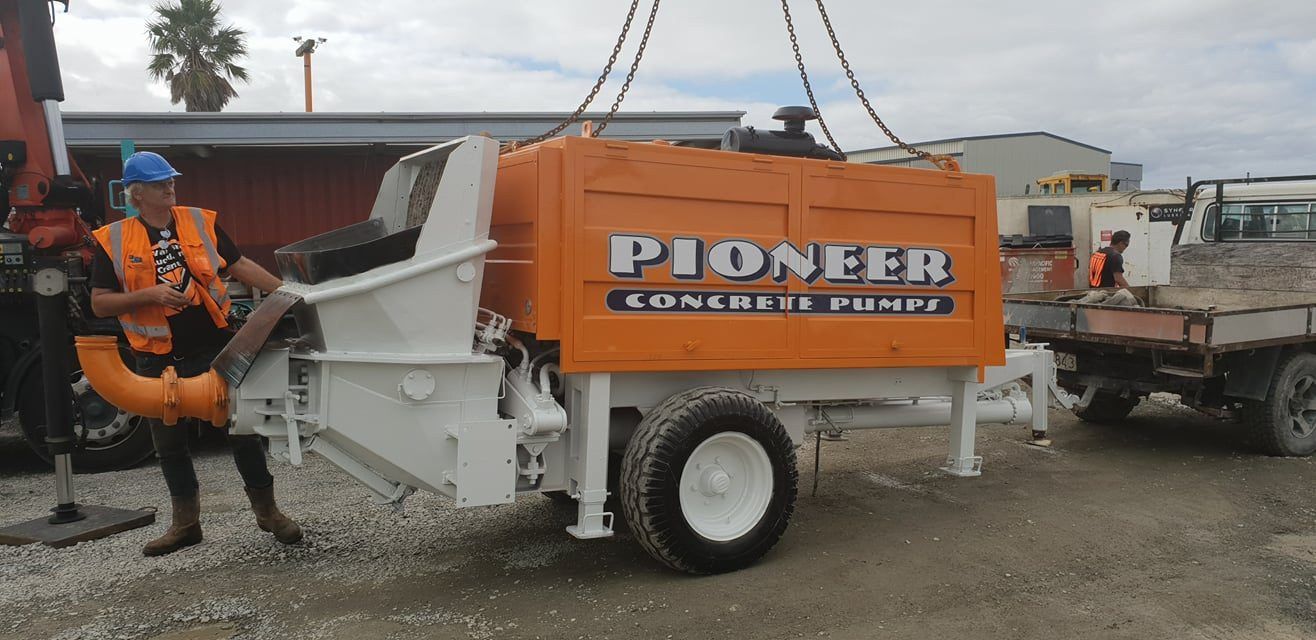 A man is standing next to a pioneer concrete pump